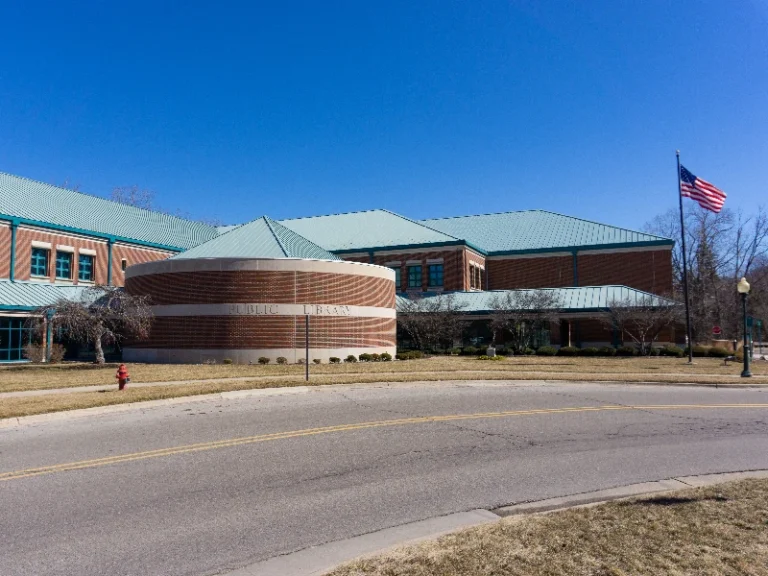 Brick public library building with a circular section and an American flag on a pole outside. water damage restoration