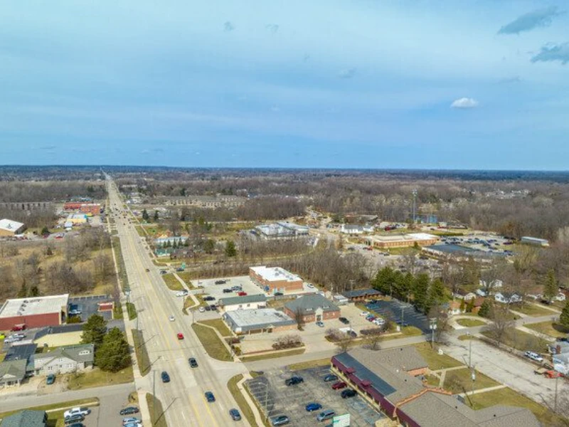 Aerial view of a suburban area with roads, buildings, and sparse trees under a blue sky. water damage restoration