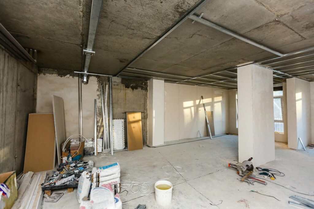 Unfinished room under construction with building materials and tools scattered on the floor.