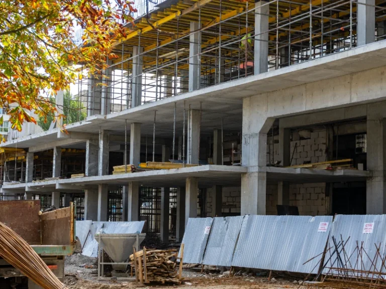 Concrete building under construction with scaffolding and metal fencing around the site. commercial restoration services